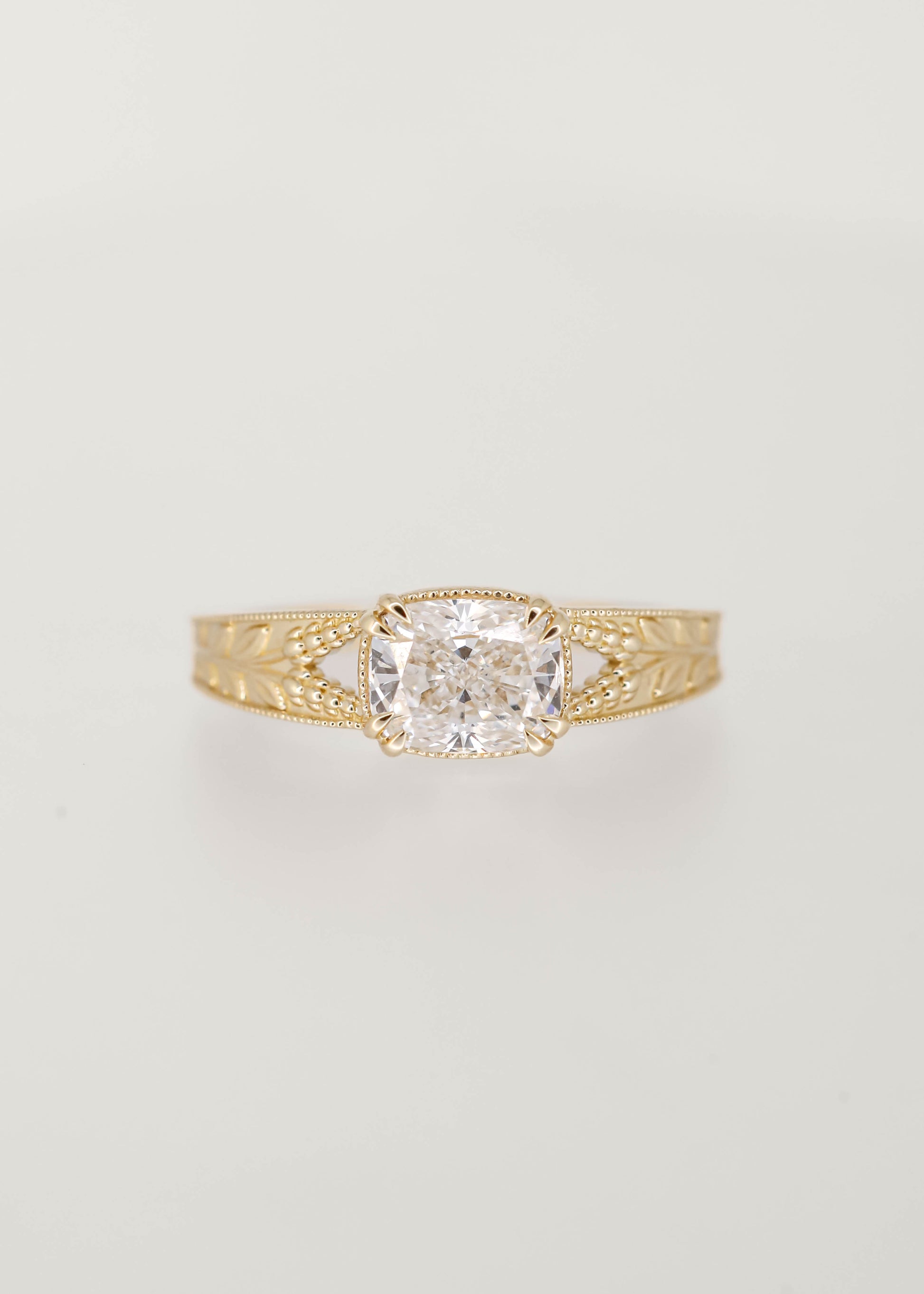 Unique lavender lesbian engagement ring with an east west elongated cushion lab grown diamond in 14K yellow gold, milgrain, and engraved lavender sprigs