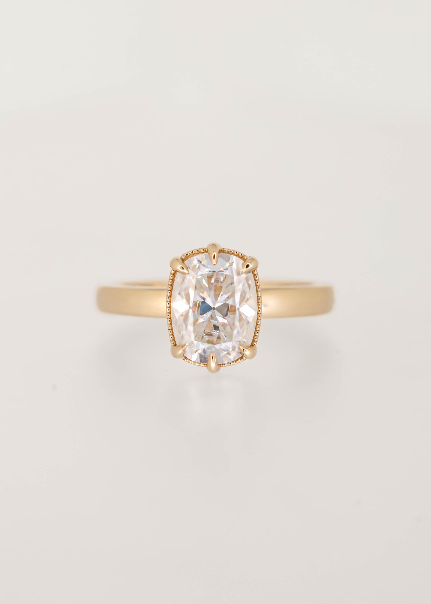 Elongated cushion moissanite solitaire engagement ring in 14K yellow gold with a six prong basket and milgrain detailing