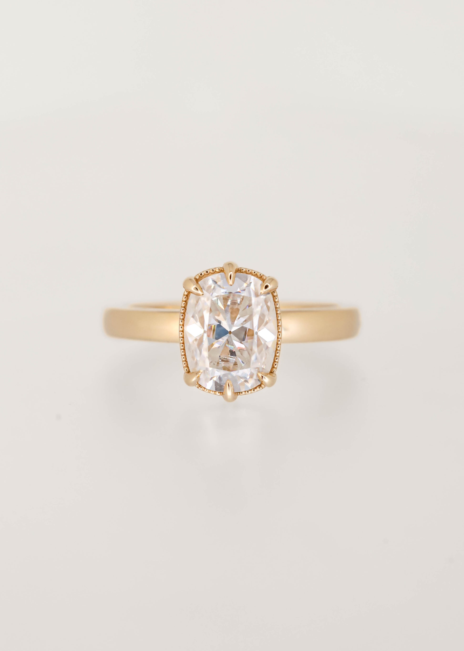 Elongated cushion moissanite solitaire engagement ring in 14K yellow gold with a six prong basket and milgrain detailing