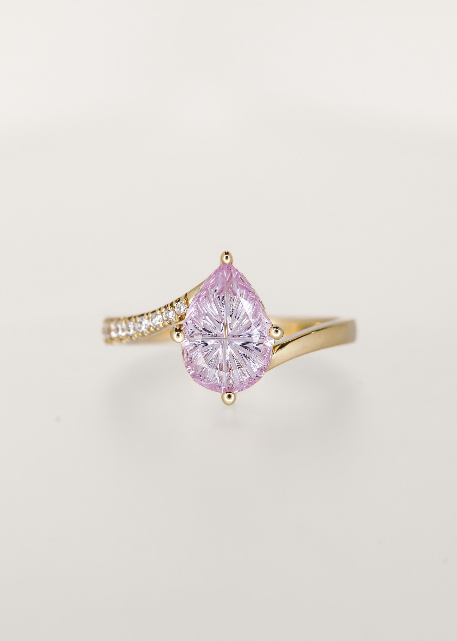 Pear cut purple sapphire fantasy cut bypass engagement ring in 14K yellow gold with radiating carved facets and a partial pavé band