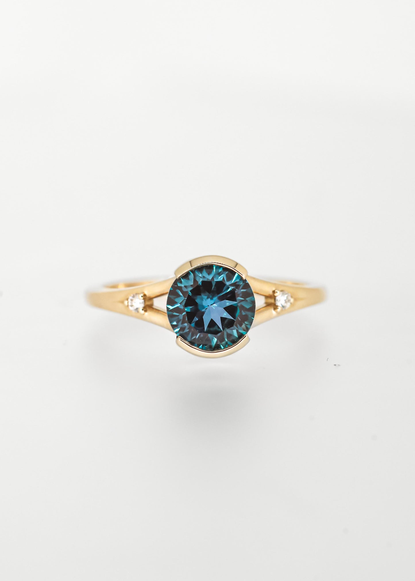 Color shifting round alexandrite engagement ring in 14K yellow gold with a half bezel, split band, and two natural diamond accents