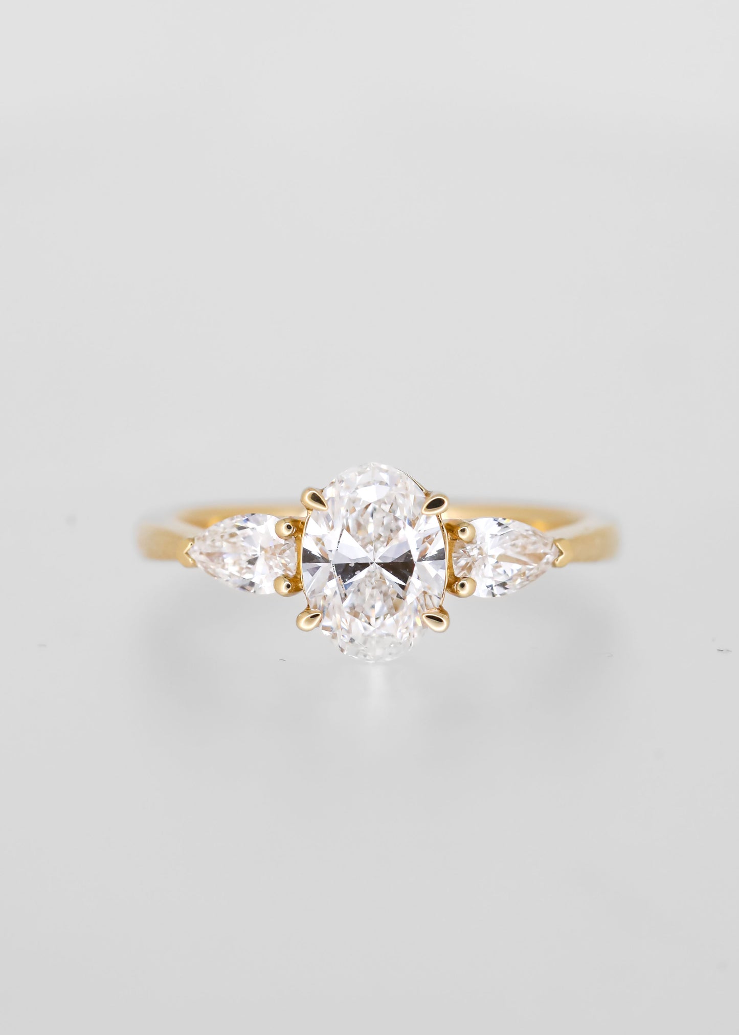 Classic oval cut lab grown diamond three stone engagement ring in 14K yellow gold with pear diamond side stones
