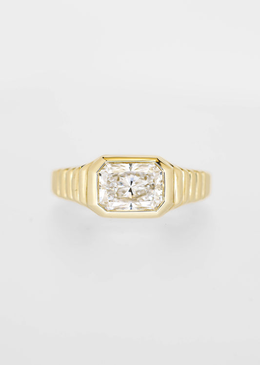 East west bezel set radiant cut lab grown diamond engagement ring in 14K yellow gold with a ribbed band