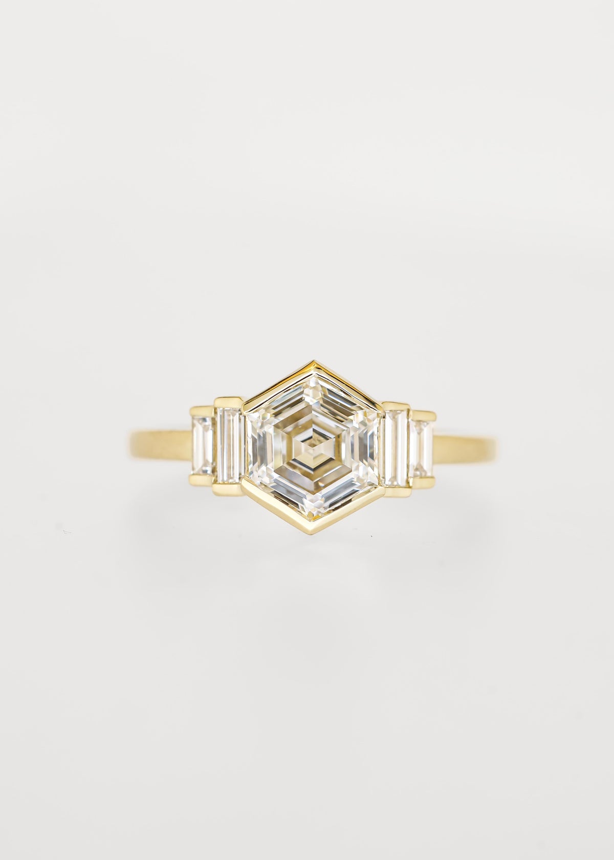 Bezel set hexagon lab grown diamond engagement ring in 14K yellow gold with graduated baguette accent stones