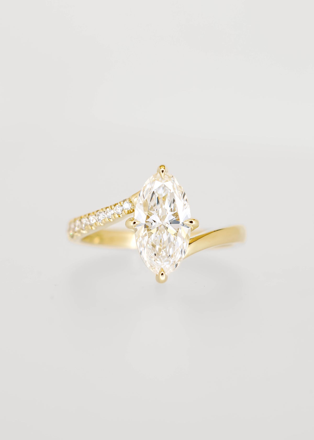 Moval cut lab grown diamond engagement ring in 14K yellow gold with an asymmetric bypass band and pavé accents
