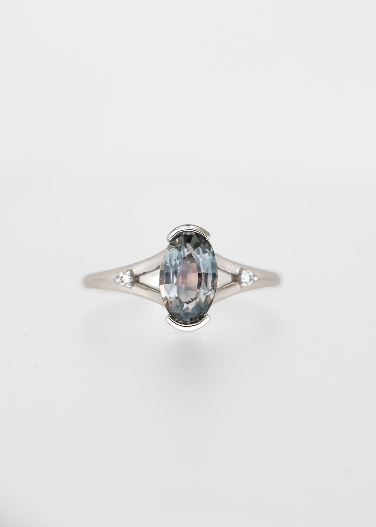 Moval cut grey blue sapphire engagement ring in 14K white gold with a split band and round diamond accents