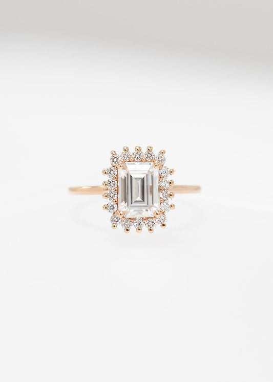 Emerald cut moissanite sunburst halo engagement ring in 14K rose gold with a round diamond halo
