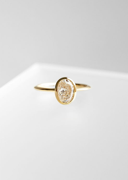 Minimal oval natural diamond bezel solitaire engagement ring in 14K yellow gold with a dainty band and low setting