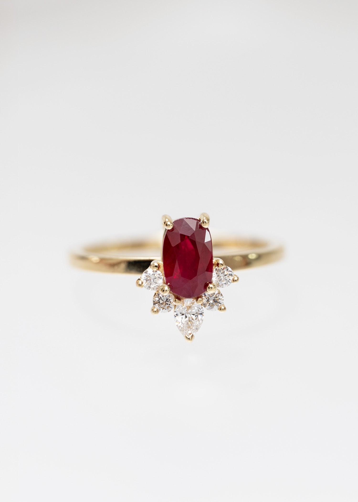 Oval ruby engagement ring in 14K yellow gold with a celestial diamond accent half-halo and pear accent