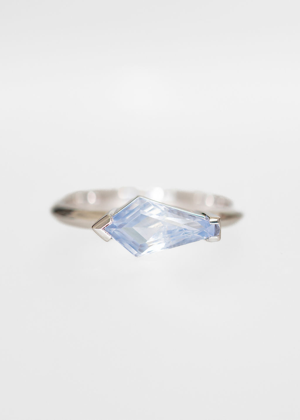 Minimal east west shield cut icy blue sapphire engagement ring in 14K white gold with half bezel setting