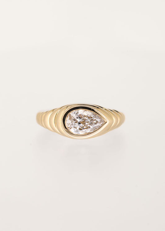 Gender neutral east west pear cut lab grown diamond engagement ring in 14K yellow gold with a sculptural ribbed signet bezel setting